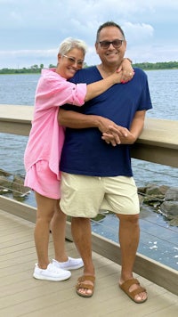 a man and woman posing for a photo by the water