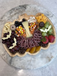 a wooden platter with a variety of fruits and cheeses on it