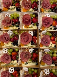 a tray of fruit, cheese and meat in a box